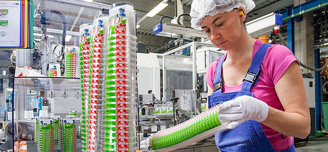 Fabrikmitarbeiterin prüft Qualität der produzierten Becher