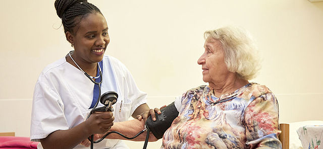 Altenpflegerin misst den Blutdruck einer älteren Frau