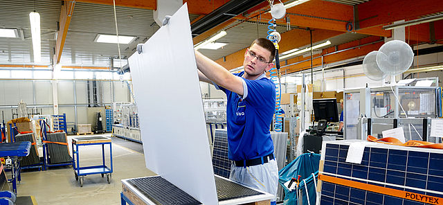Mitarbeiter prüft ein Solarmodul in der Produktion